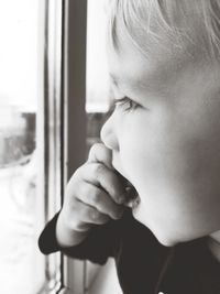 Close-up portrait of boy looking through window