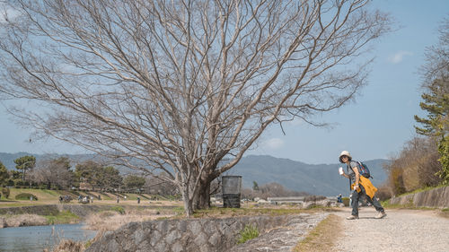 Rear view of woman walking on field against sky