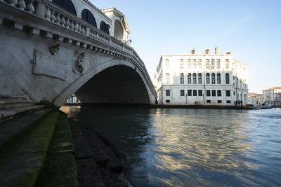 Arch bridge over river against buildings in city