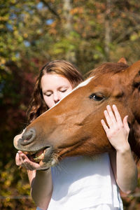 Young woman stroking horse at farm