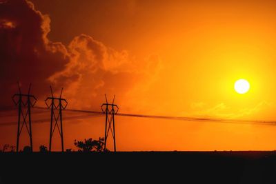 Silhouette electricity pylon against sky during sunset