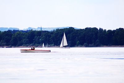 Sailboat sailing on lake against clear sky