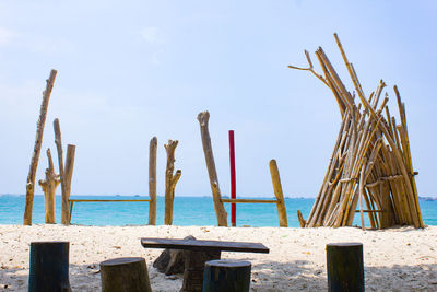 Wooden posts on beach against sky