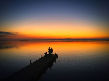 Silhouette man by sea against sky during sunset