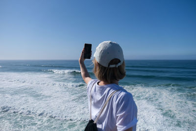 Rear view of man on beach against clear sky