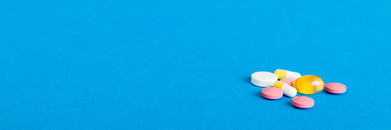 Close-up of pills spilling from bottle against blue background