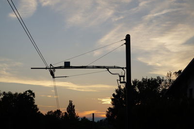 Low angle view of silhouette electricity pylon against sky