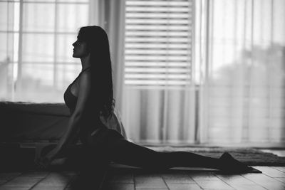 Side view of young woman exercising at home