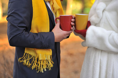 Midsection of man and women holding coffee mugs