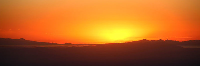Panoramic view of silhouette landscape against orange sky during sunset