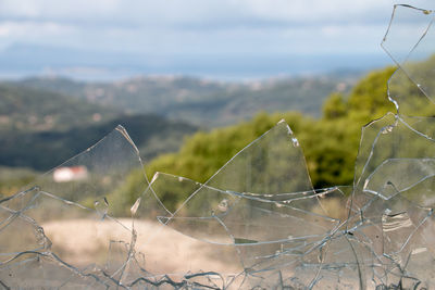 Close-up of broken glass on field against sky