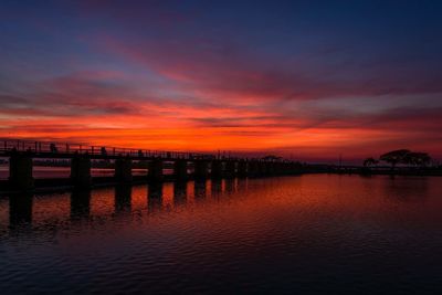 Pier in sea at sunset