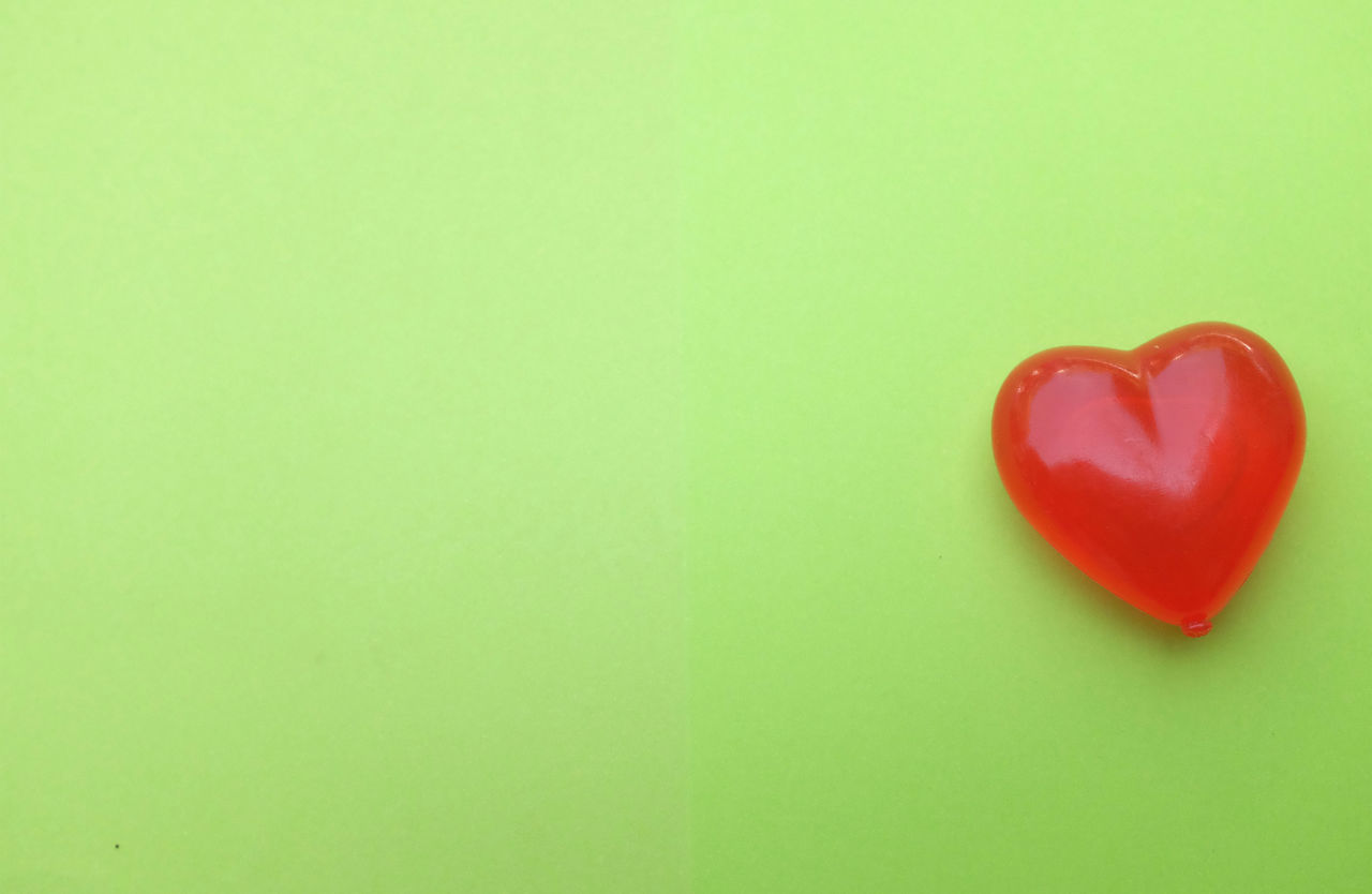 CLOSE-UP OF RED HEART SHAPE OVER GREEN BACKGROUND