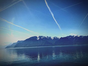 Scenic view of lake and mountains against blue sky