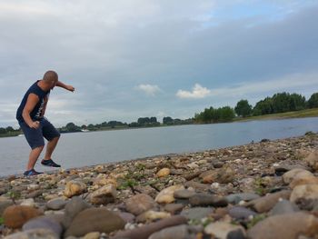 Full length of man on rocks at shore against sky