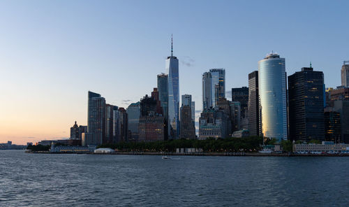 Lower manhattan skyline at sunset viewed from the water.