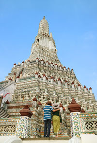 Couple climbing up to phraprang, central spire of wat arun temple, landmarks of bangkok, thailand