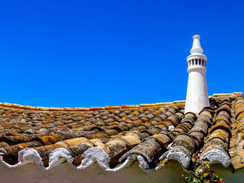 Low angle view of roof and building against clear blue sky