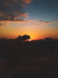 Silhouette person holding orange sky during sunset