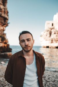 Portrait of man standing at beach against sky