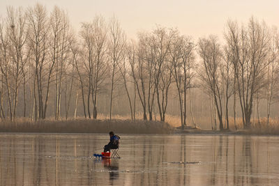 Man sitting in lake against sky