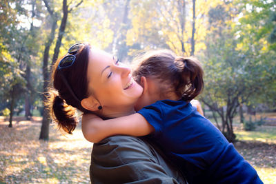 Portrait of smiling young woman against trees