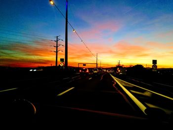 Cars on road against sky during sunset