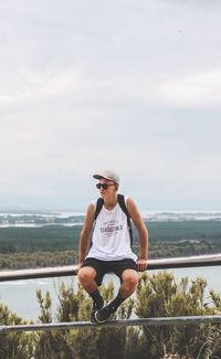 Full length of young man wearing sunglasses standing against sky