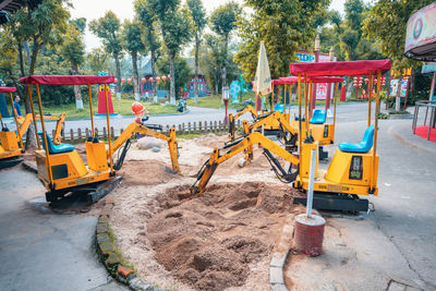 Construction site by road against trees in city