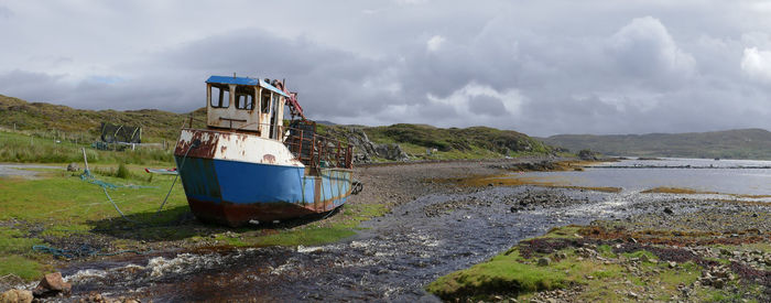 Boat moored on beach against sky