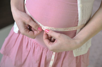 Midsection of woman measuring abdomen with tape