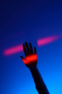 Close-up of hand against blue sky