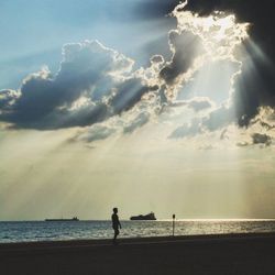 Silhouette person standing on beach against sky