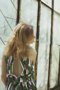 Pretty lady from behind standing by window scenic photography