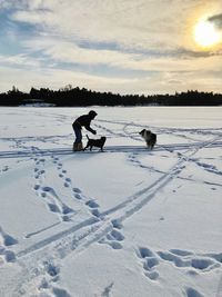People on snow field against sky during sunset