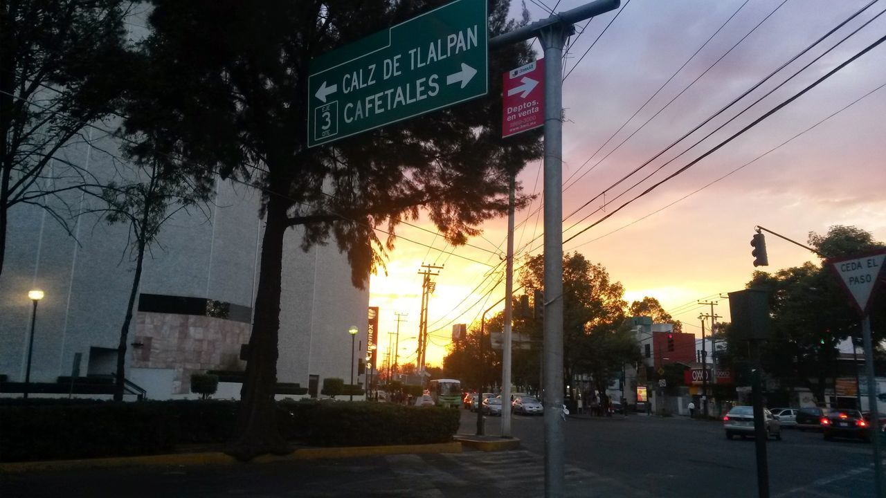 building exterior, architecture, built structure, city, sunset, communication, text, street, road sign, western script, guidance, road, street light, sky, transportation, information sign, city life, city street, sign, car