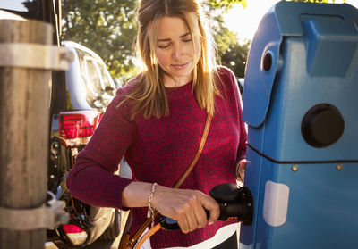 Mature woman plugging cable at station