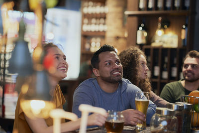 Happy friends watching soccer match at bar