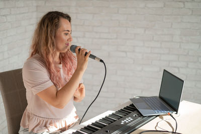 Young woman using laptop while sitting on table