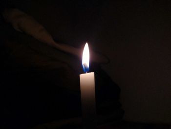 Close-up of illuminated candle in darkroom