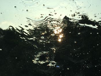 Full frame shot of wet glass against sky during sunset