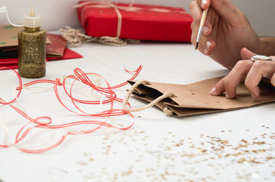 Cropped image of hand decorating paper bag on table