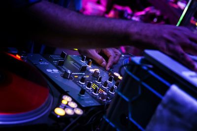 Cropped image of dj using sound mixer at club