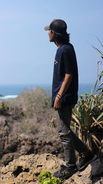 Full length of young man standing by sea against clear sky