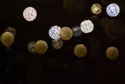 Low angle view of illuminated light bulbs hanging at night