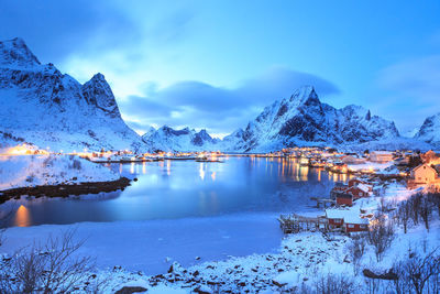 Scenic view of lake and snowcapped mountains against sky at lofoten during dusk
