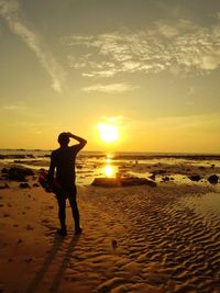 Silhouette man standing on beach against sky during sunset