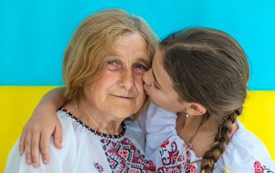 Girl kissing grandmother against ukrainian flag
