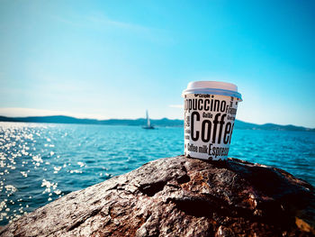 Close-up of disposable coffee cup against sky