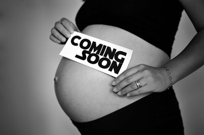 Midsection of pregnant woman with text coming soon